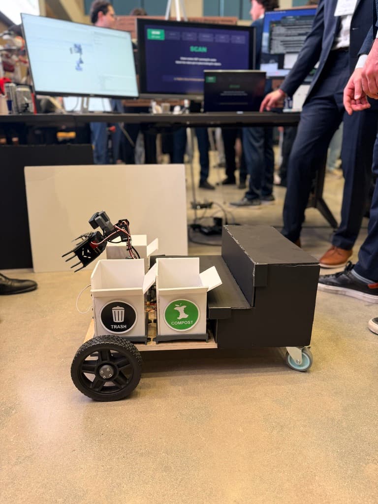The RECLAIM robot on the capstone showcase floor: drive base, sensor mast, and 4-DOF sorting arm